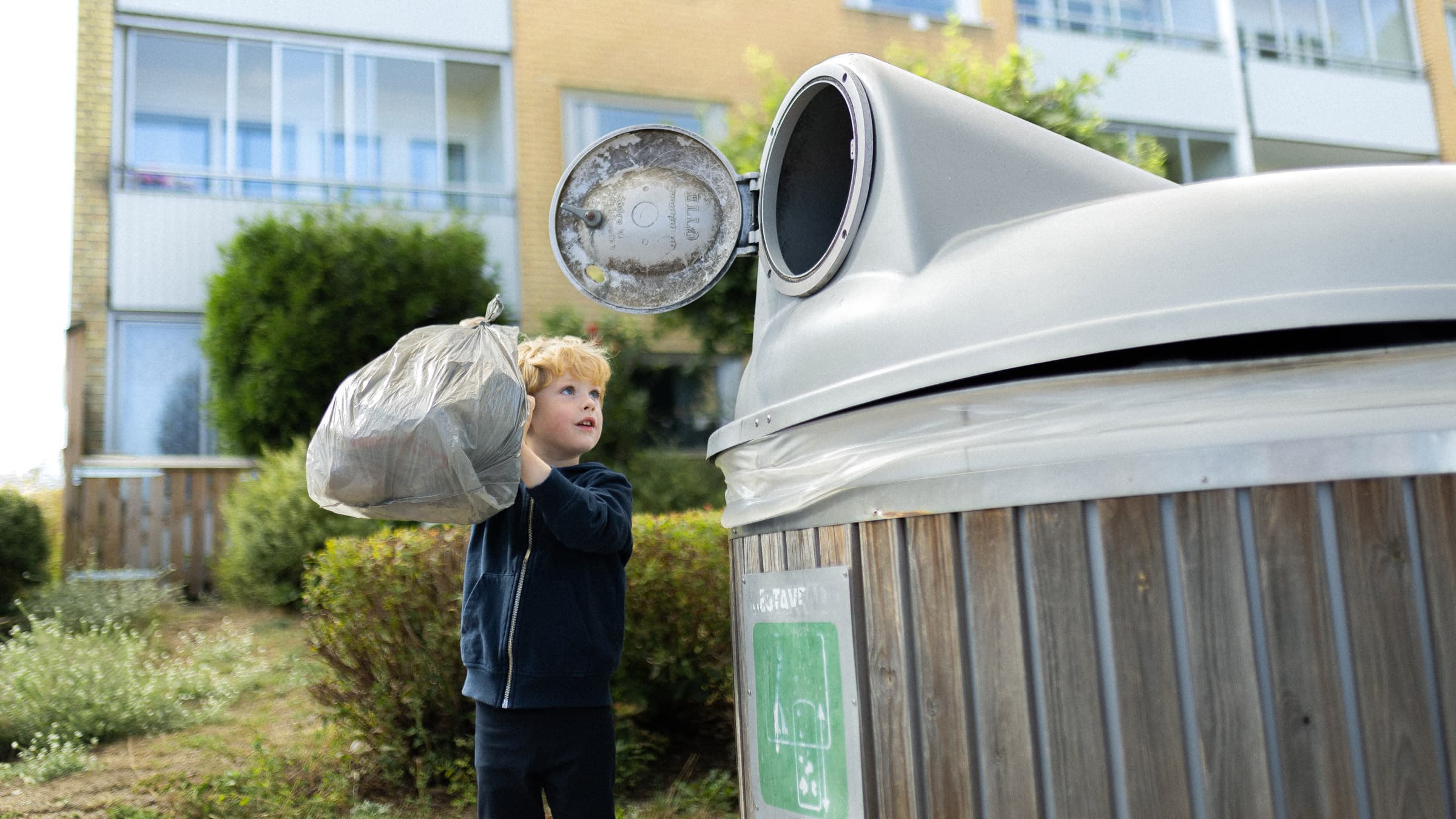 Pojke slänger soppor i ett sopkärl